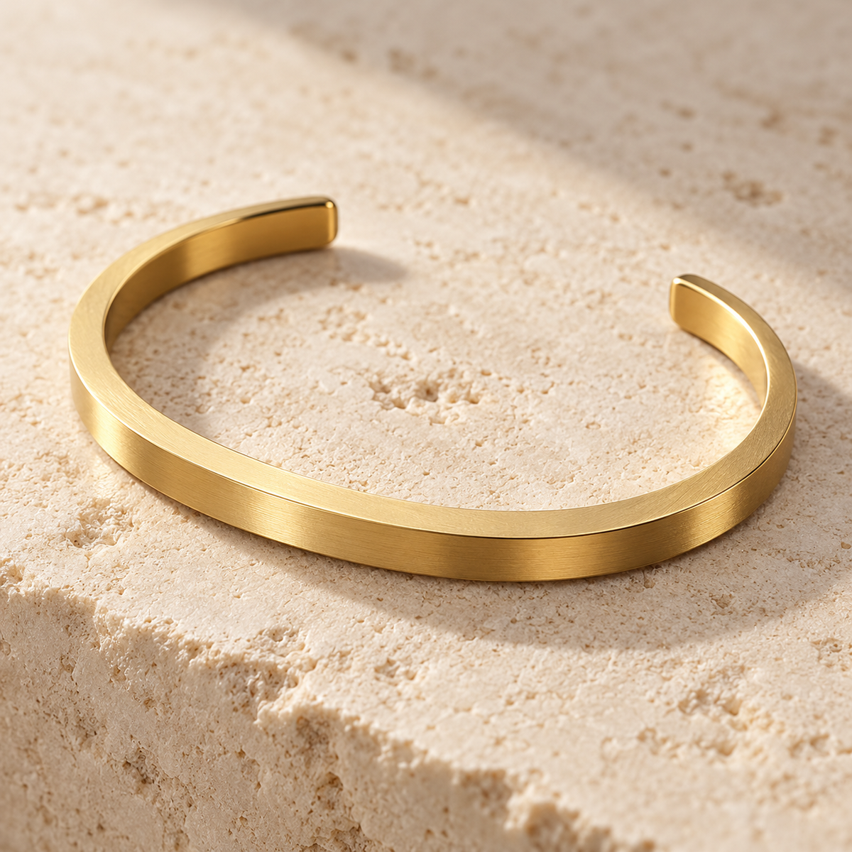 The Arc Cuff — Gold-tone detail view on cream stone