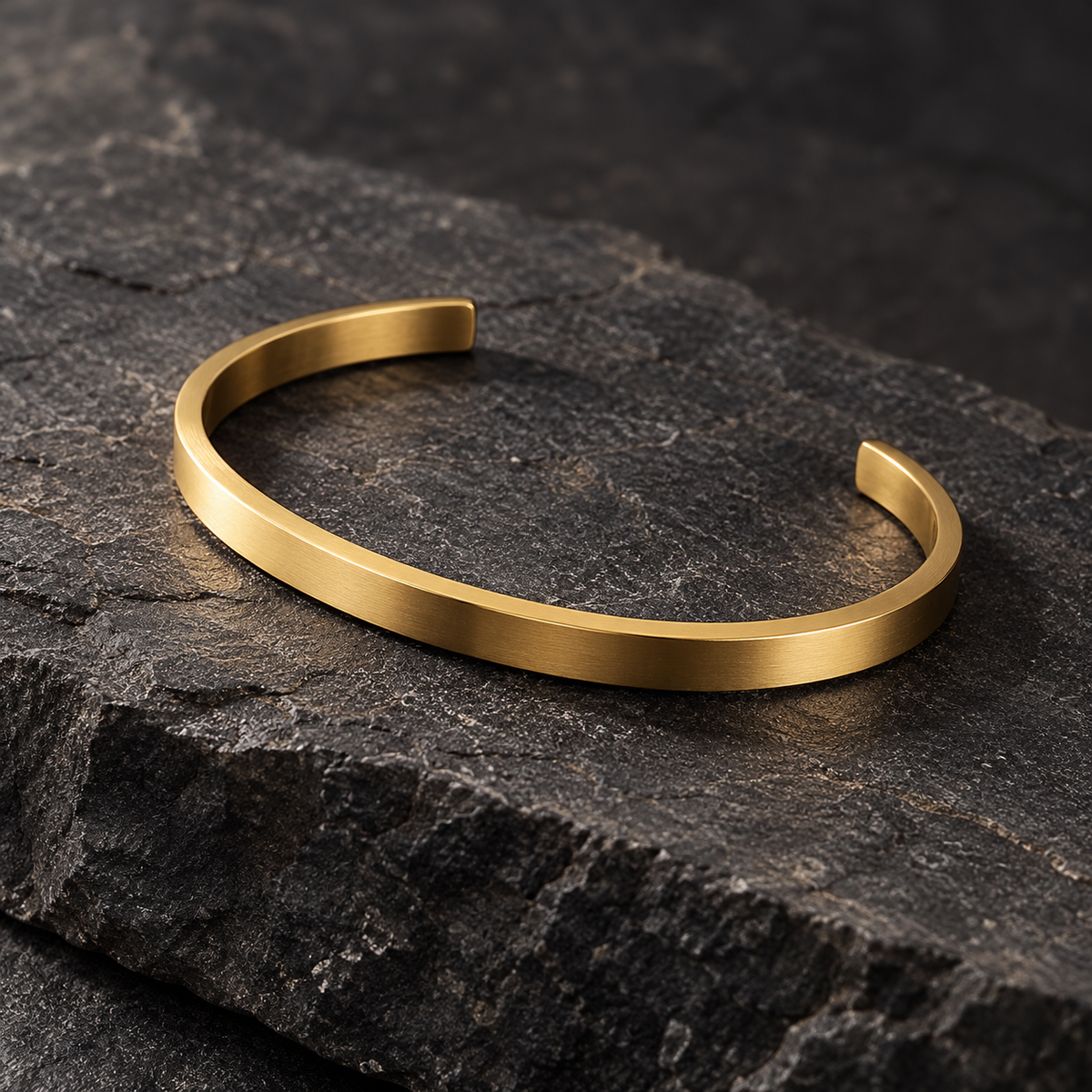 The Arc Cuff — Gold-tone editorial view on charcoal stone