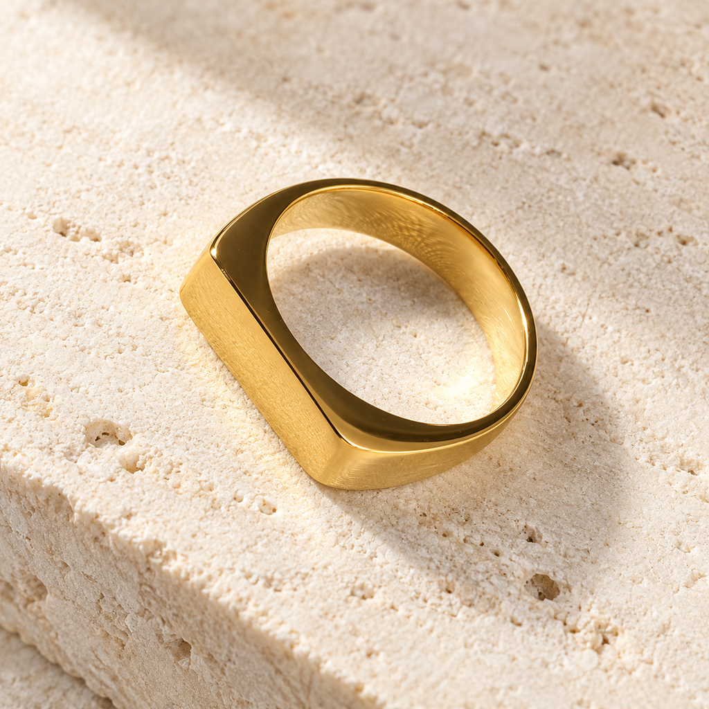 The Frame Signet — Gold-tone detail view on cream stone