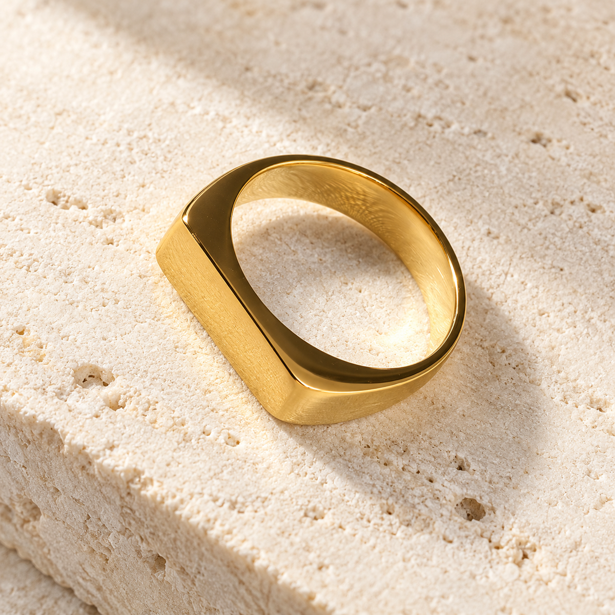 The Frame Signet — Gold-tone detail view on cream stone