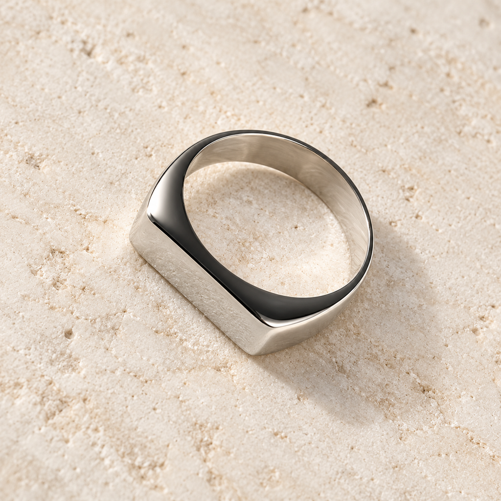 The Frame Signet — Silver-tone detail view on cream stone